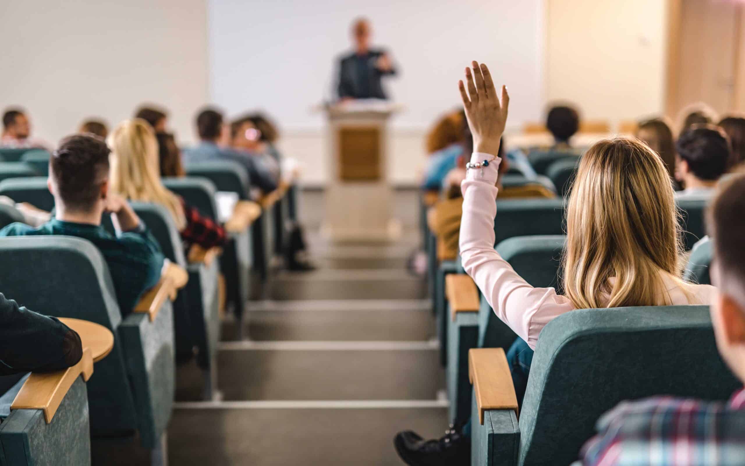 Person som räcker upp handen i en undervisningssal