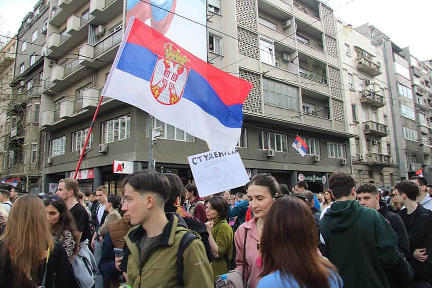 Serbisk flagga och människor som demonstrerar i Belgrad